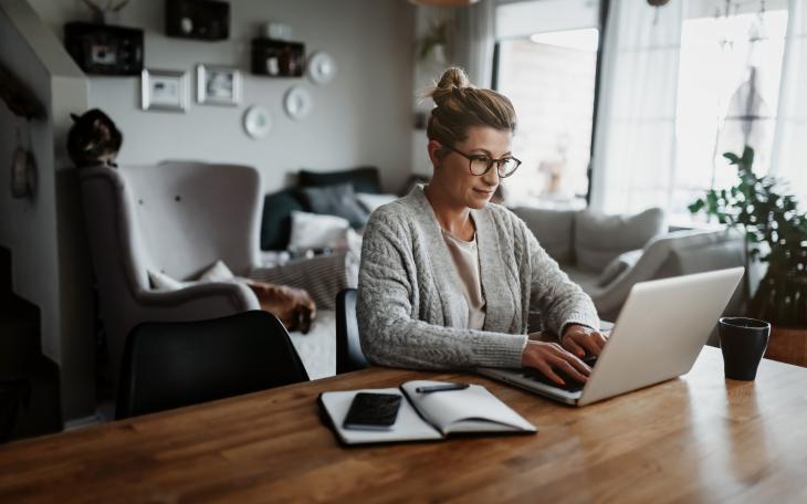 Woman sat at a table typing on a laptop