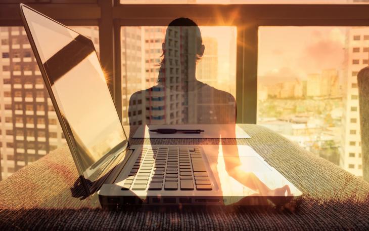 Shadow of a woman doing yoga, with a laptop in the background