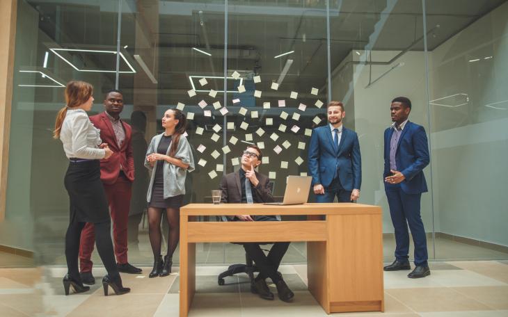 6 people in a meeting room with notes on the wall