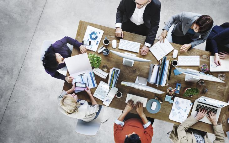 Overhead view of people working on a wooden table