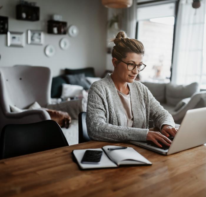 Woman sat at a table typing on a laptop