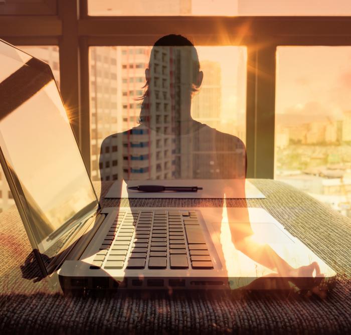 Shadow of a woman doing yoga, with a laptop in the background