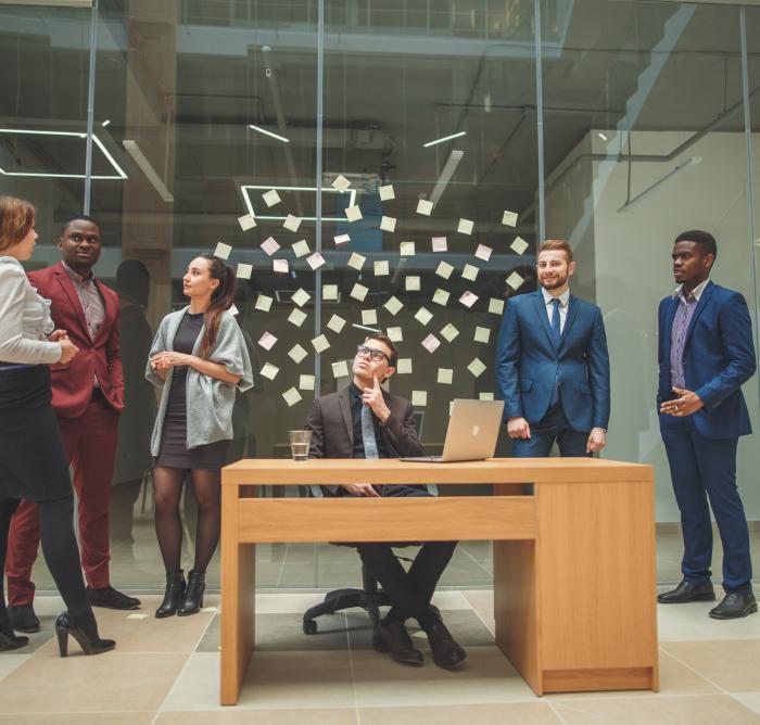 6 people in a meeting room with notes on the wall