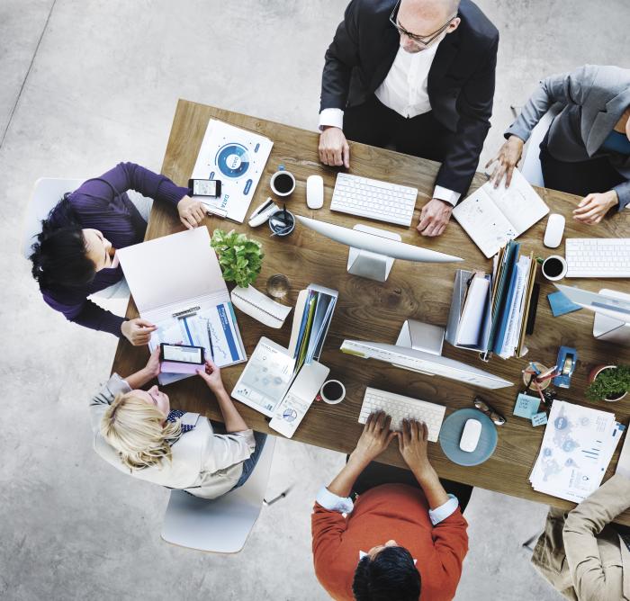 Overhead view of people working on a wooden table